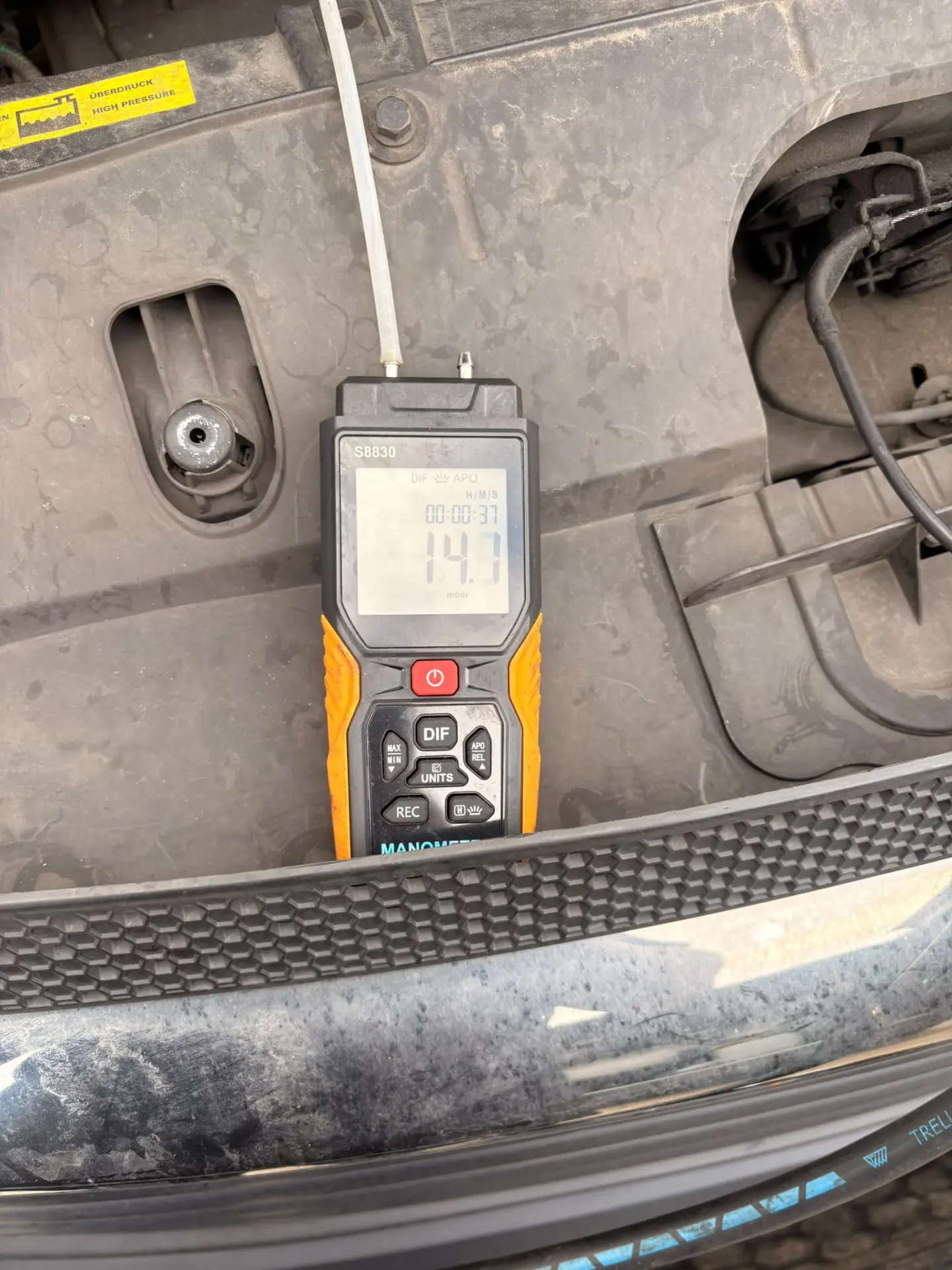 Manometer connected to a vehicle's DPF system displaying a low differential pressure reading of 14.7 mbar after DPF cleaning
