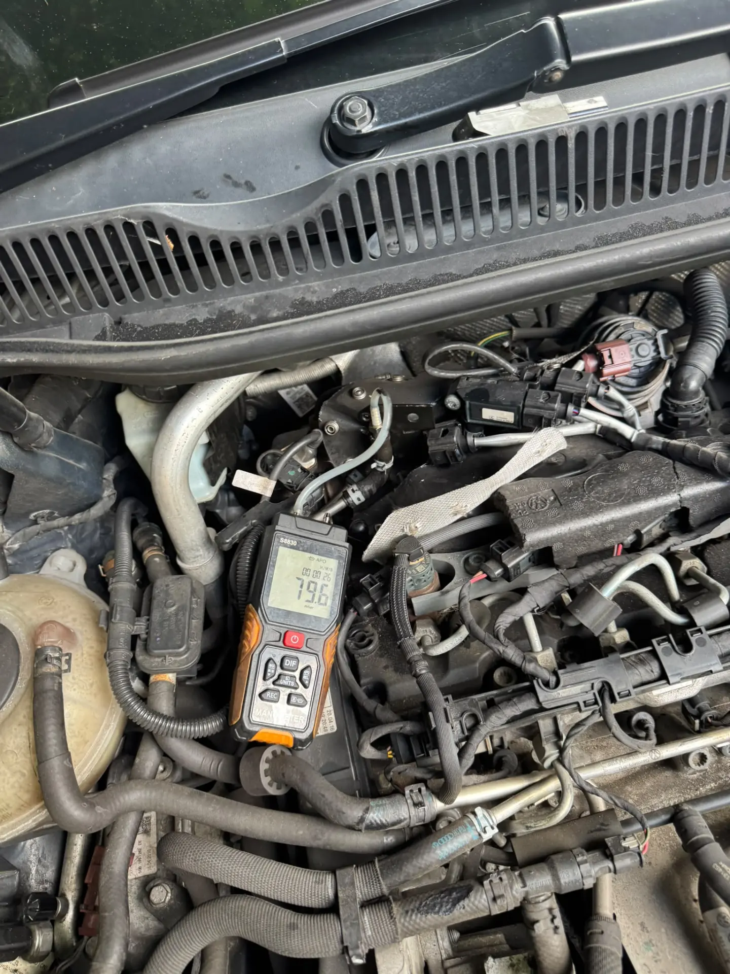 Technician performing a DPF pressure test with a digital manometer connected to a diesel engine before cleaning.