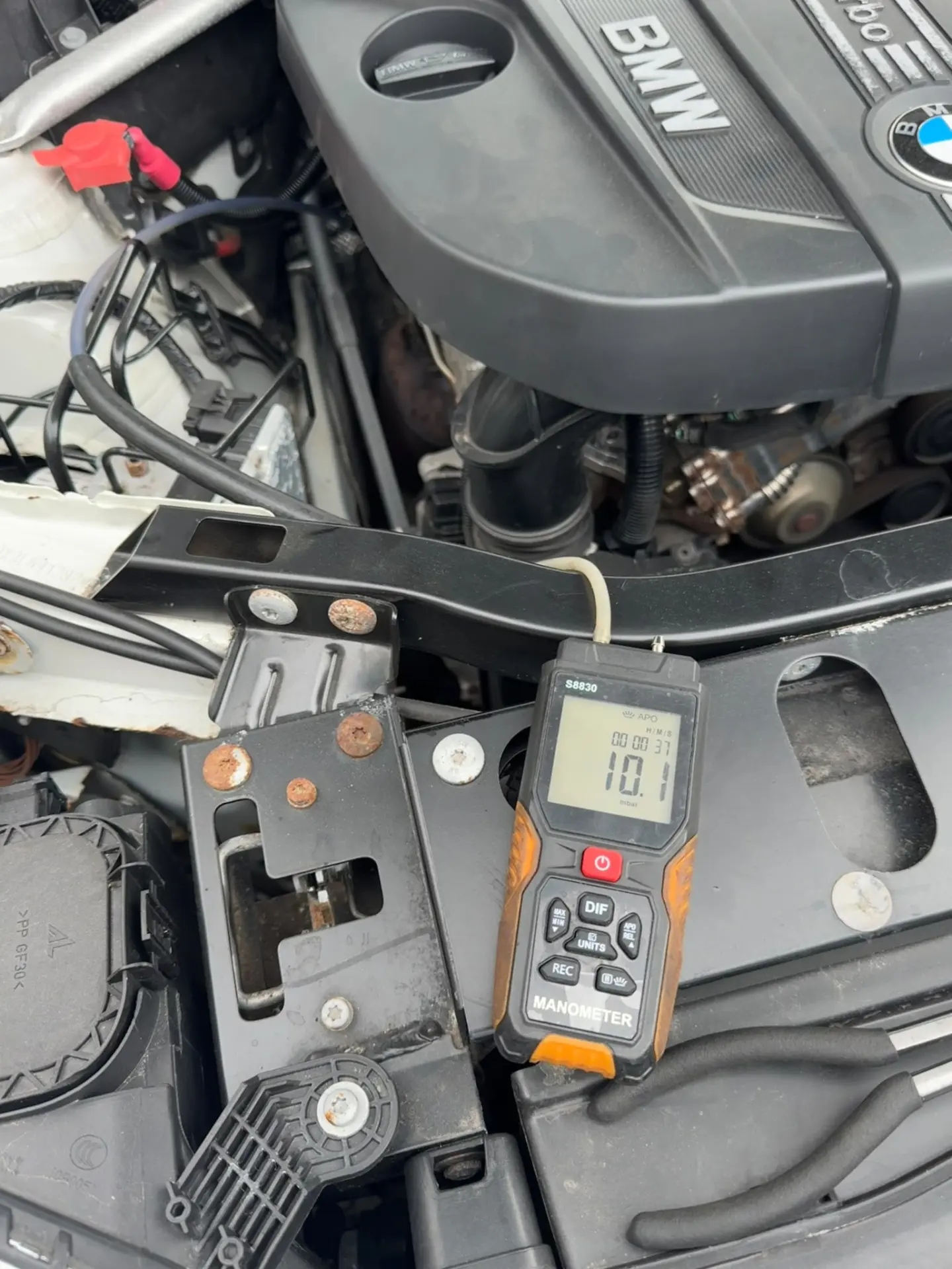 Digital manometer showing a 10.1 mbar DPF pressure reading on a BMW X3 before professional DPF cleaning.
