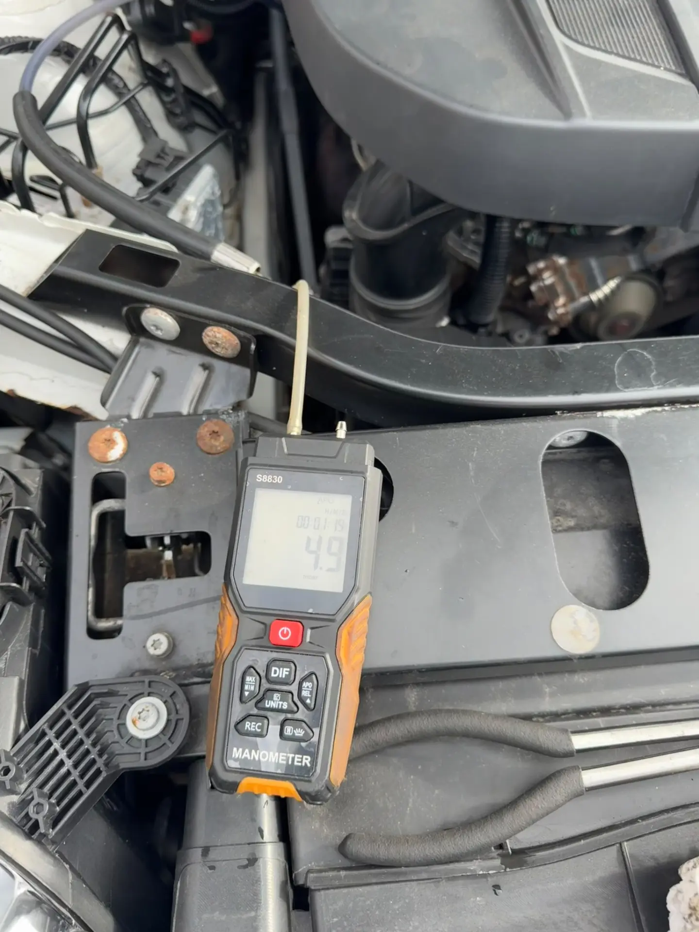 Digital manometer showing a reduced 4.9 mbar DPF pressure reading on a BMW X3 after professional DPF cleaning.