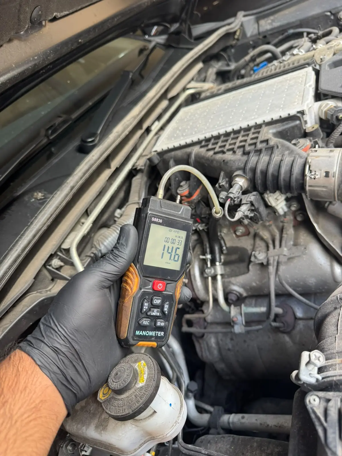 Digital manometer measuring 14.6 mbar exhaust back pressure before Toyota Hilux DPF cleaning.