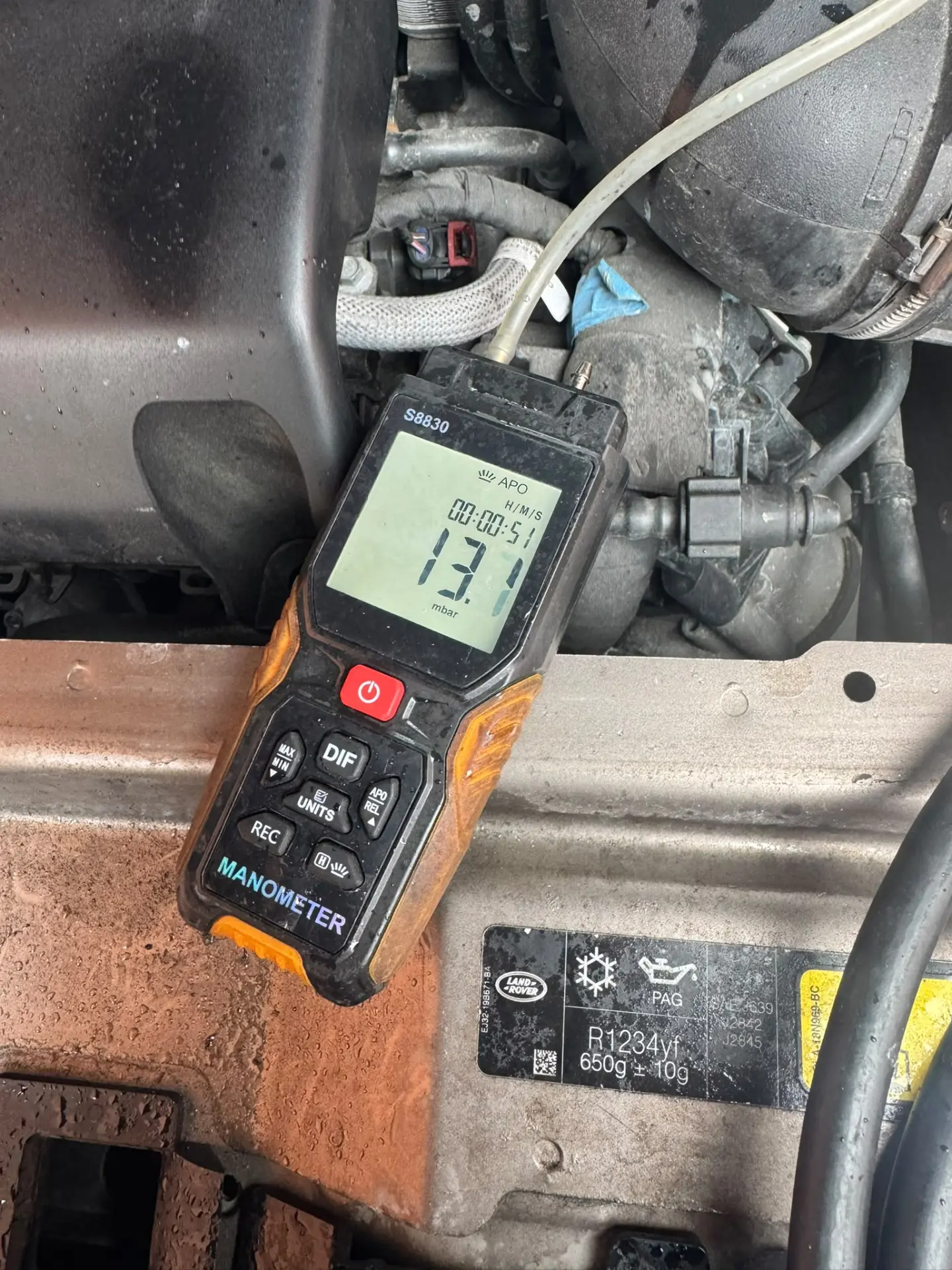 Engine bay of a Land Rover Discovery Sport after DPF cleaning, with a digital manometer displaying an improved pressure reading of 13.1 mbar following the service.