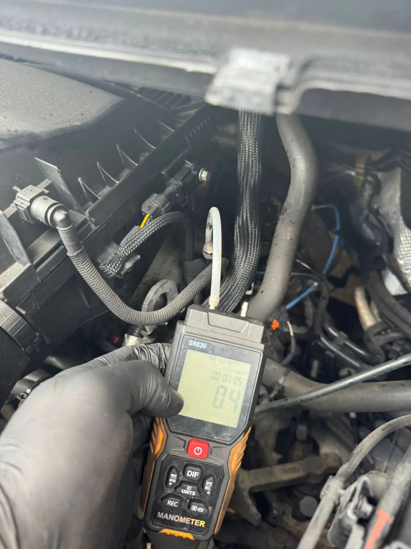 Technician using a digital manometer to measure differential pressure after completing a DPF cleaning service on a Ford Transit, showing a reading of 0.4 mbar.