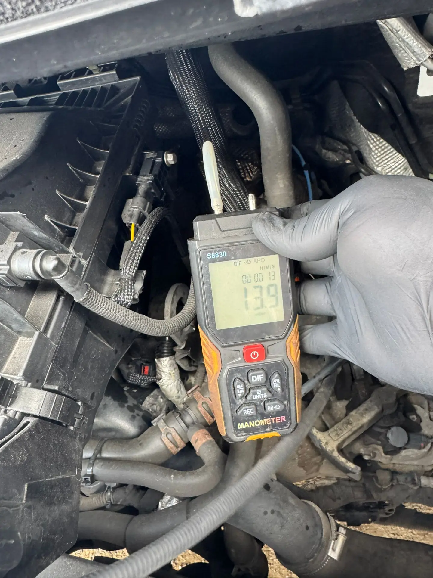 Digital manometer connected to a Ford Transit engine bay during initial DPF diagnostics, displaying a differential pressure reading of 13.9 mbar.