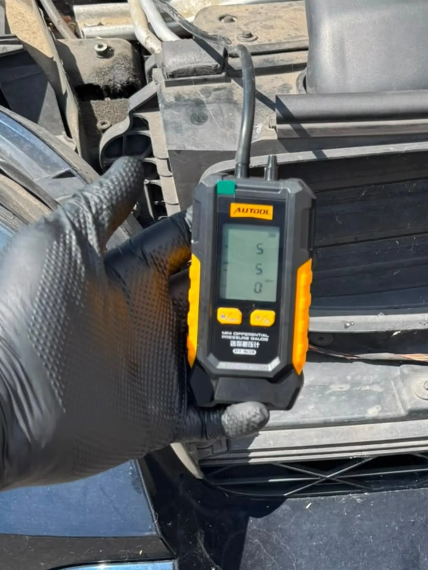 BMW X5 with bonnet open during DPF pressure testing using a digital differential pressure gauge before professional DPF cleaning.