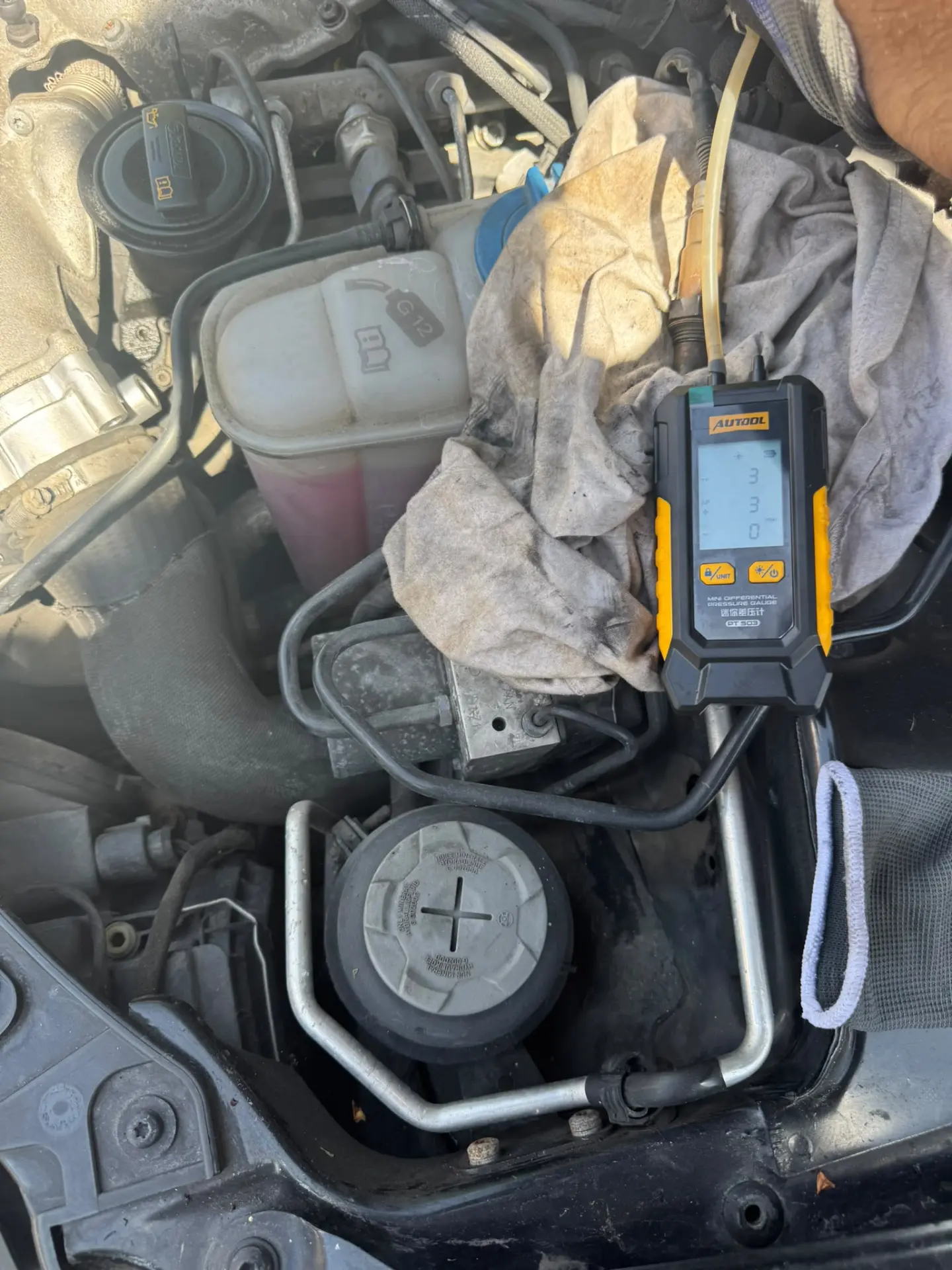 AUTool differential pressure gauge connected to a diesel engine for professional DPF diagnostics and performance assessment during an on-site cleaning service.
