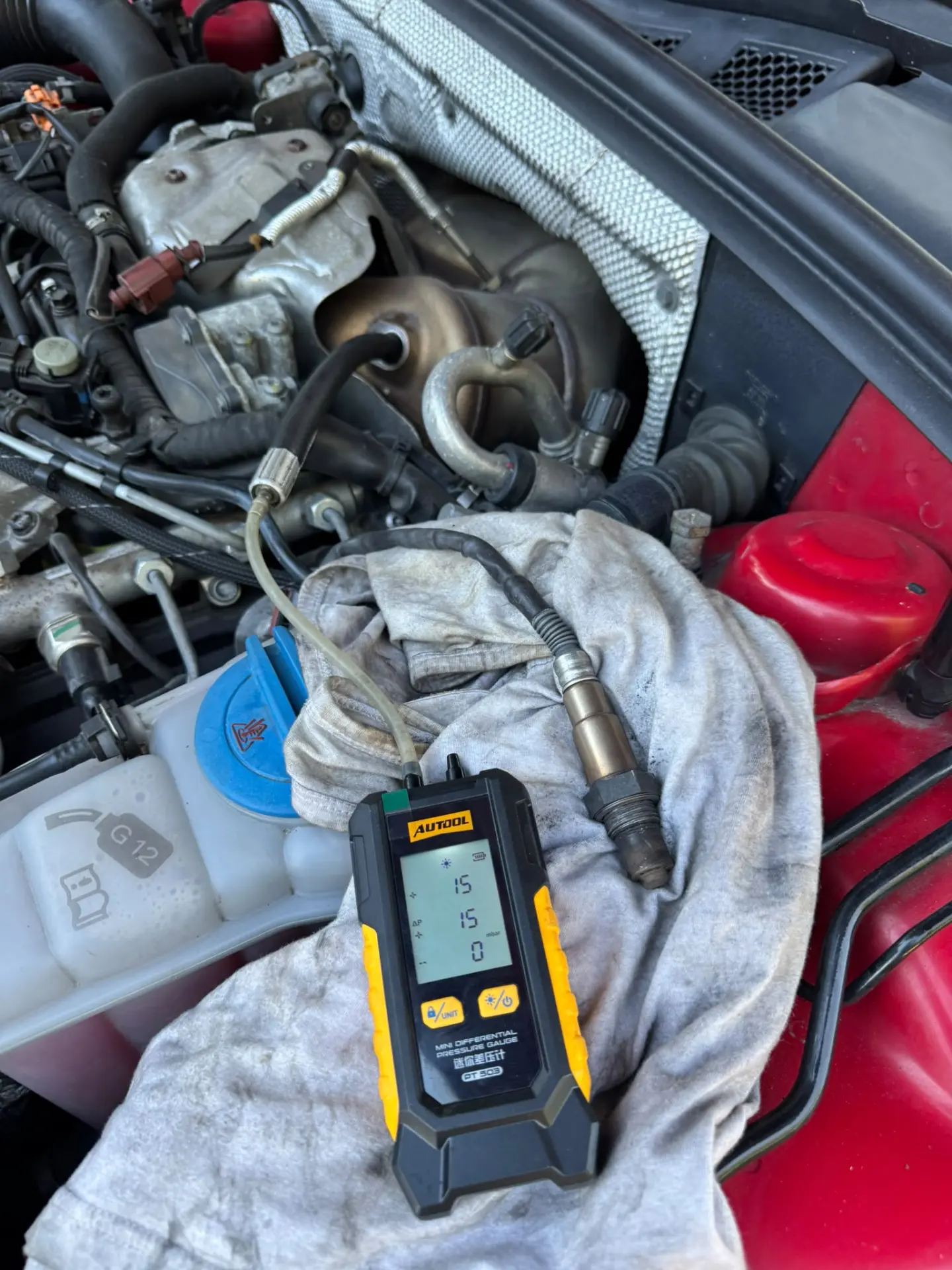 AUTool differential pressure gauge connected to an Audi A4 engine, displaying 15 mbar DPF pressure before professional DPF cleaning.