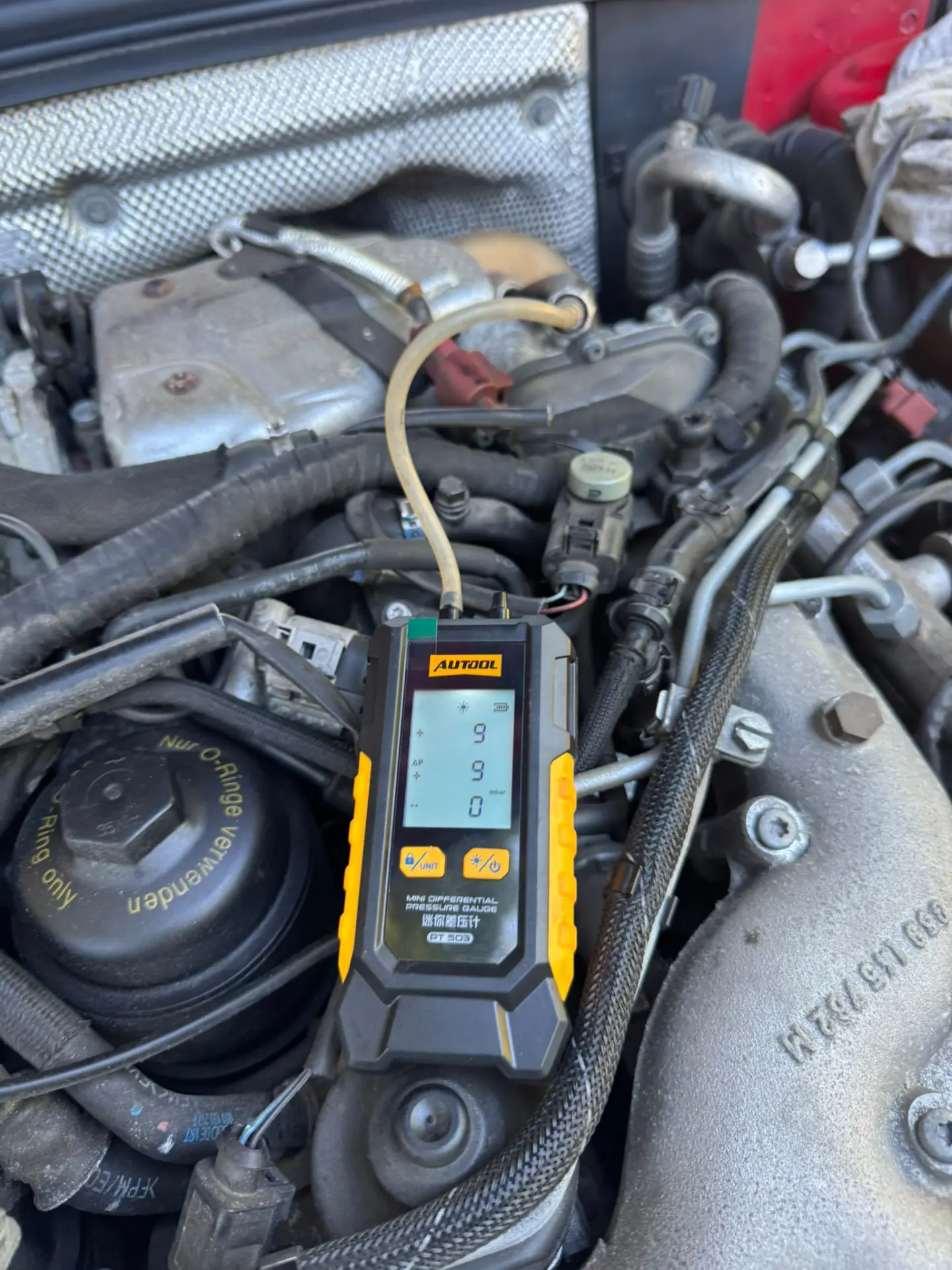 AUTool differential pressure gauge connected to an Audi A4 engine, displaying 9 mbar DPF pressure after successful DPF cleaning, indicating improved exhaust flow.