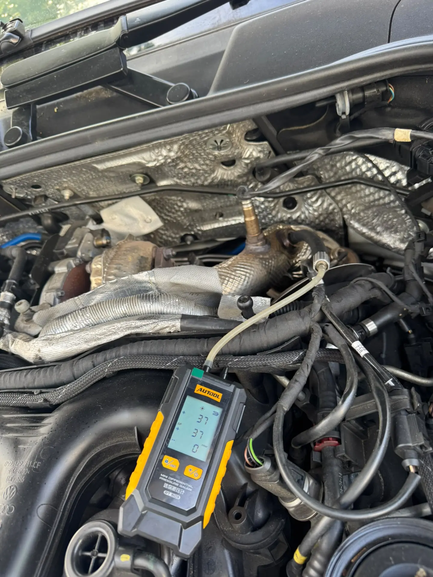 Digital DPF pressure gauge displaying a reduced 37 mbar reading after professional DPF cleaning on a Porsche Cayenne engine.