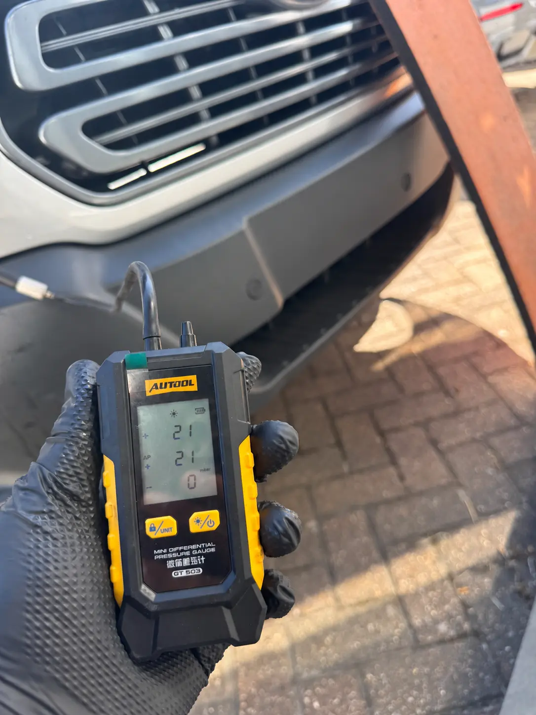 Digital pressure gauge displaying 21 mbar in front of a Ford Transit after DPF cleaning.