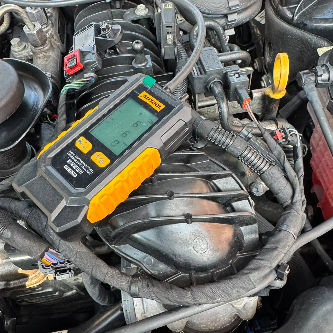 DPF diagnostic testing using a digital pressure gauge to check exhaust pressure and identify potential diesel particulate filter blockage.